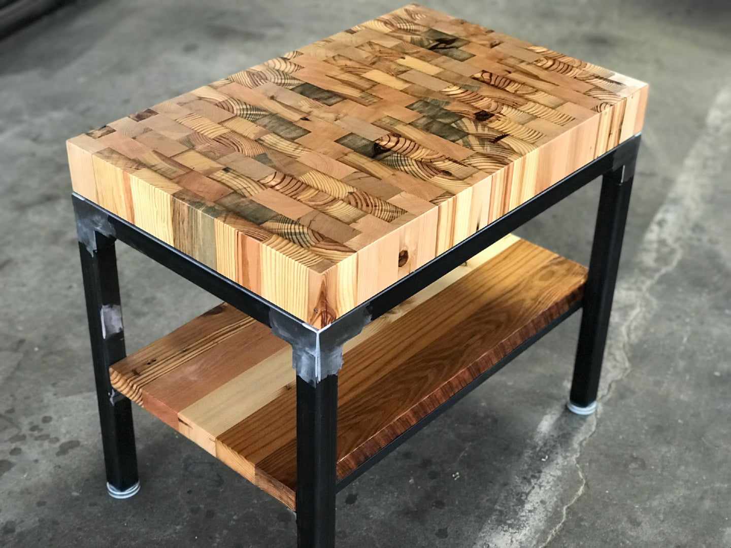 Butcher Block End Grain End Table with Shelf by Workshop Detroit - Made from reclaimed wood and shown wit a aclear natural finish sitting on a concrete floor