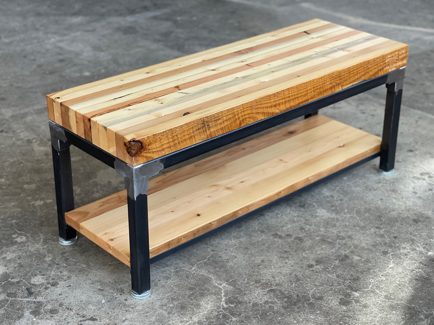 Grand Boulevard Entry Bench by Workshop Detroit sitting on a concrete floor - Made from reclaimed lumber and steel and shown in a clear coat finish