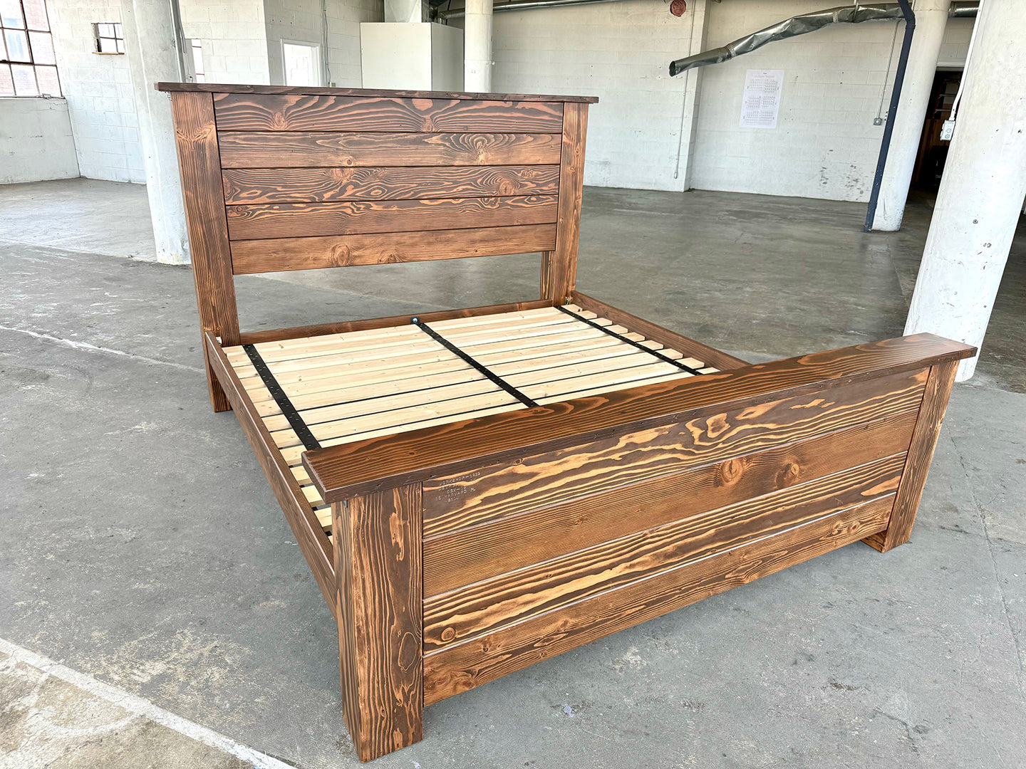 The Leland Bed by Workshop Detroit - Shown in a loft space with a concrete floor and white walls - Made from reclaimed lumber